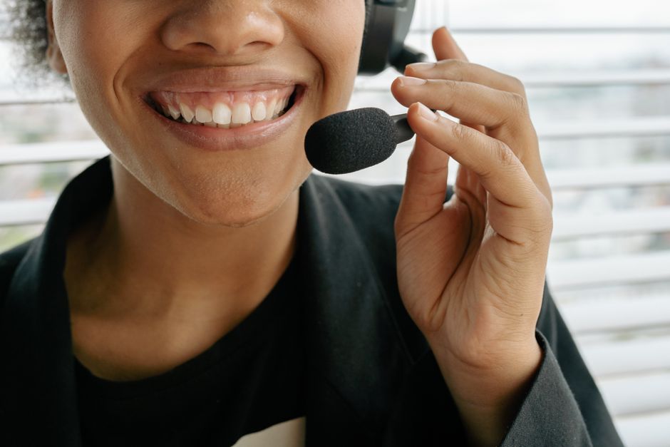 Close-up de uma representante de call center sorridente segurando um microfone.
