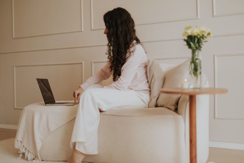 Mulher trabalhando em um laptop em um escritório doméstico minimalista com tons neutros suaves e um ambiente tranquilo.