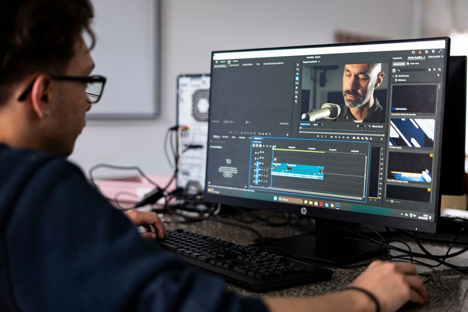 Um editor de vídeo trabalhando em um projeto usando um computador de mesa em um ambiente de escritório moderno.