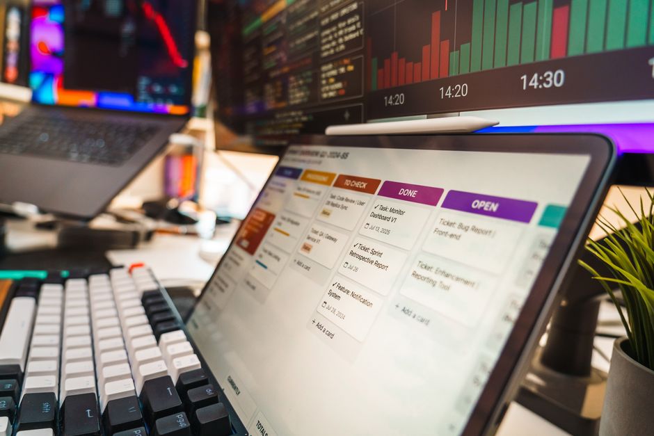 Um ambiente de escritório dinâmico com vários monitores exibindo gráficos de dados e ferramentas de gerenciamento de projetos, perfeito para ambientes tecnológicos ou empresariais.